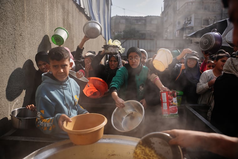 Palestinians wait to receive donated food at a community kitchen in Nuseirat, central Gaza Strip, on Wednesday, Dec. 17.