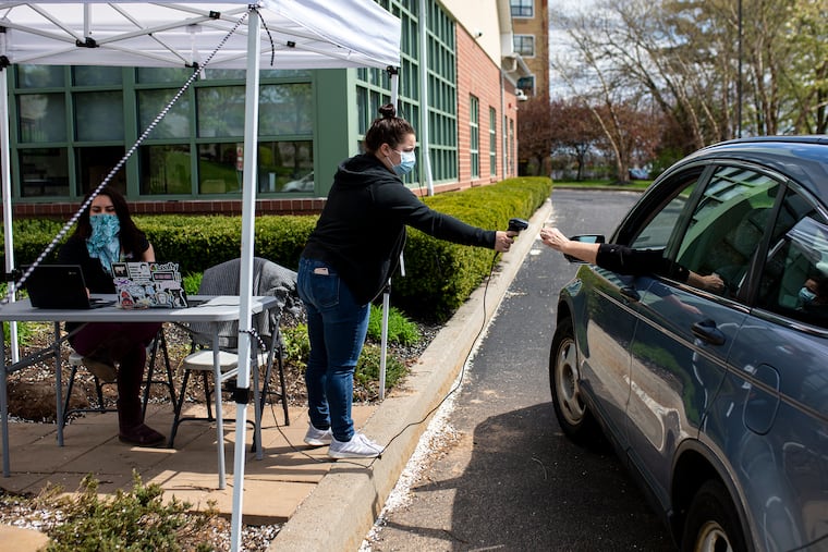 Amanda Light, 25, of Norristown, Pa., Floor Supervisor at Apothecarium Dispensary, center, checks in Sheila Helge, 61, of Ambler, Pa., right, picking up an order from The Apothecarium Dispensary on Wednesday, April 8, 2020. “I’m glad that they now have a drive through and I don’t have to go inside,” Helge said.