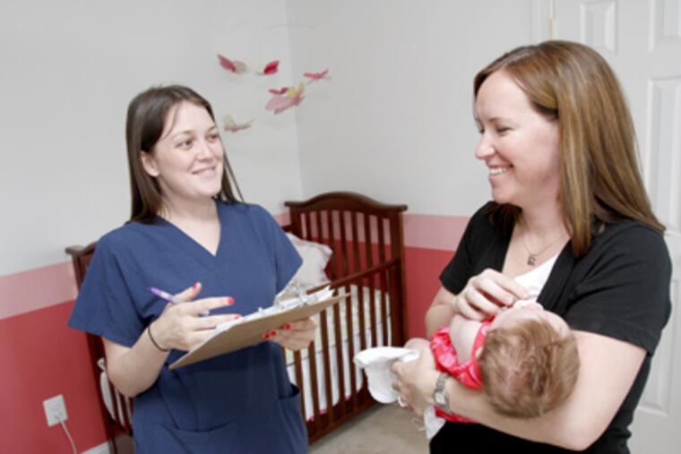 Samantha Yocum sleeps in the arms of her mother, Beth Yocum, joined by Drexel program staffer Lauren Clay. (Charles Fox / Staff Photographer)