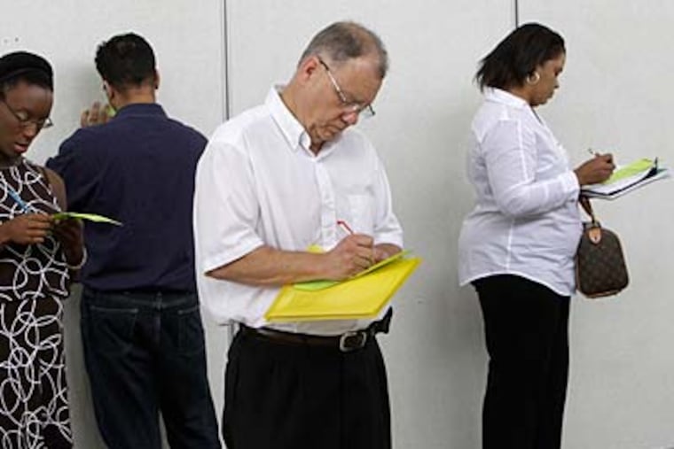 Job seekers fill out registration forms to attend a job fair in Southfield, Mich. (AP Photo/Paul Sancya)