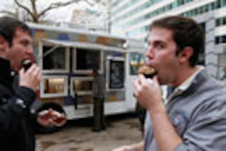 Andy Campbell (left) and Brian Wing (right) eat cupcakes purchased from the Cupcake Truck.