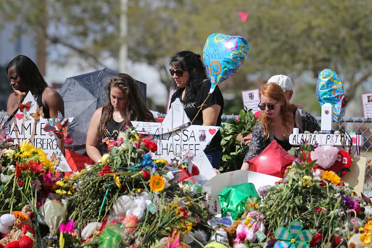 In this Feb. 25, 2018 photo, mourners bring flowers as they pay tribute at a memorial for the victims of the shooting at Marjory Stoneman Douglas High School, in Parkland, Fla. The community is focusing on suicide prevention programs after two survivors of the Florida high school massacre there killed themselves this month.