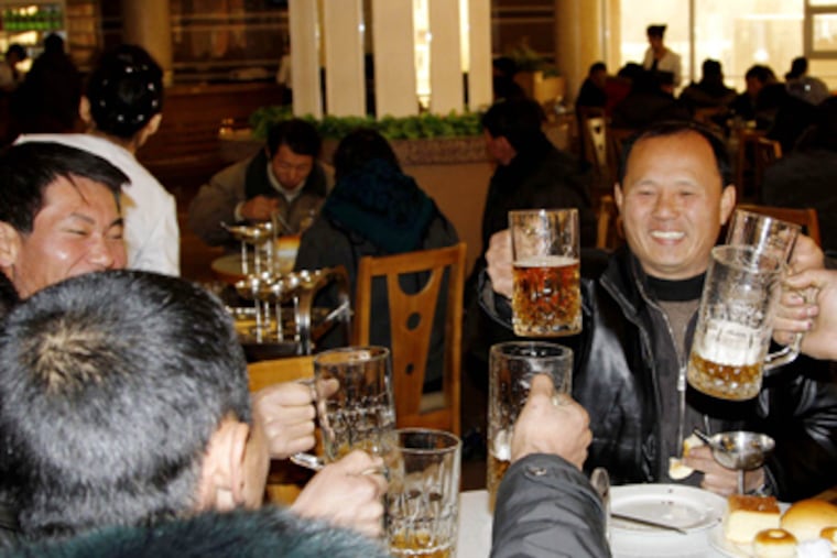 North Koreans hoist their beer glasses after hearing the news of a successful rocket launch. KIM KWANG HYON / AP