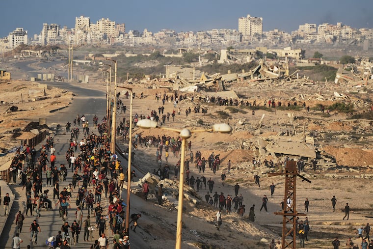 Israeli tanks are positioned on the coastal road leading to Gaza City as displaced Palestinians gather near Wadi Gaza in the central Gaza Strip, Thursday, Oct. 9, 2025. (AP Photo/Abdel Kareem Hana)