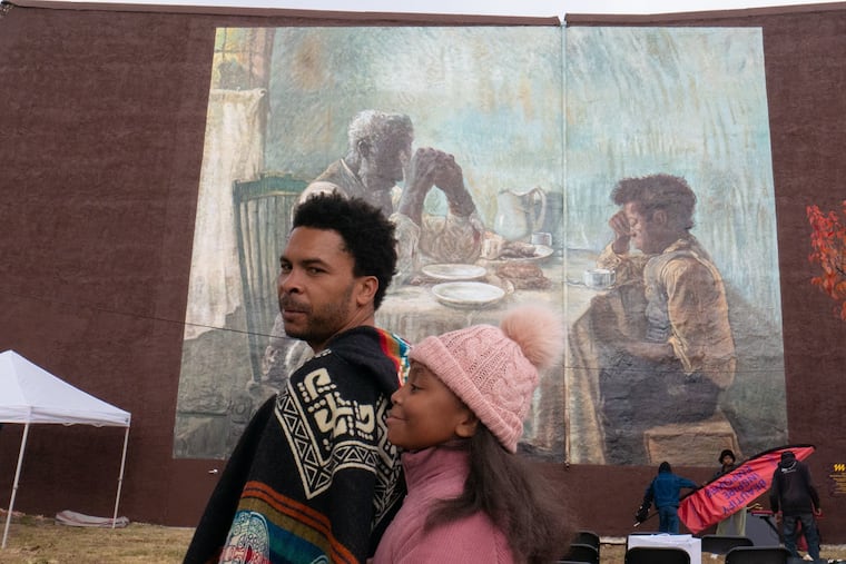 George Anthony Morton, curator of "The Thankful Poor" mural, which was dedicated on a wall of Gethsemane FHB Church in Strawberry Mansion on Sunday, Nov. 24, 2024, is pictured with his daughter, Nuri, age 9.