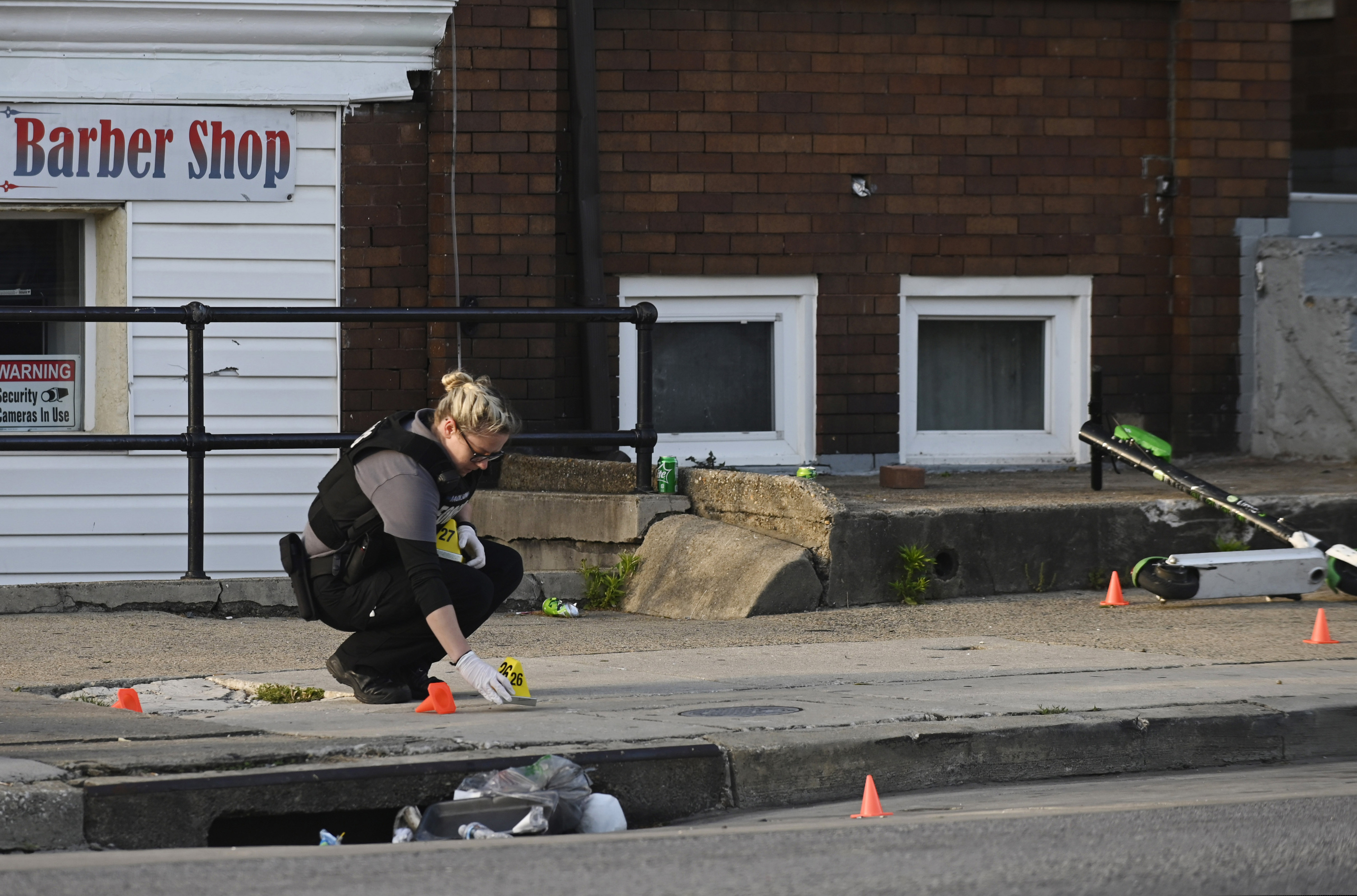 A Baltimore police forensics officer places an evidence marker next to a bullet casing while investigating the scene of a shooting in Baltimore on Sunday, April 28, 2019. A gunman fired indiscriminately into a crowd that had gathered for Sunday afternoon cookouts along a west Baltimore street, killing at least one person and wounding several others, authorities said.