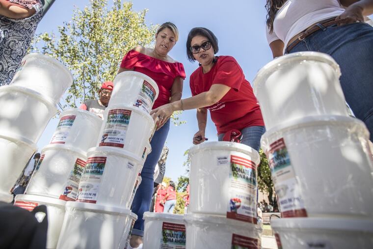 Reverend Jessie Alejandro (left) and Madeline Neris-Negro of Unidos Pa’ PR stack up the plastic donation buckets used during Sunday’s Puerto Rico Day Parade to solicit money for the island after the devastation of Hurricane Maria.