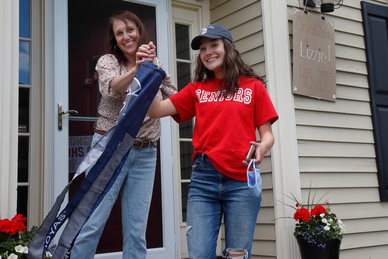 Hgh school graduate Lizzie Quinlivan and her mom, Julie, hold a Georgetown University windsock at their home in Hingham, Mass., in June.
