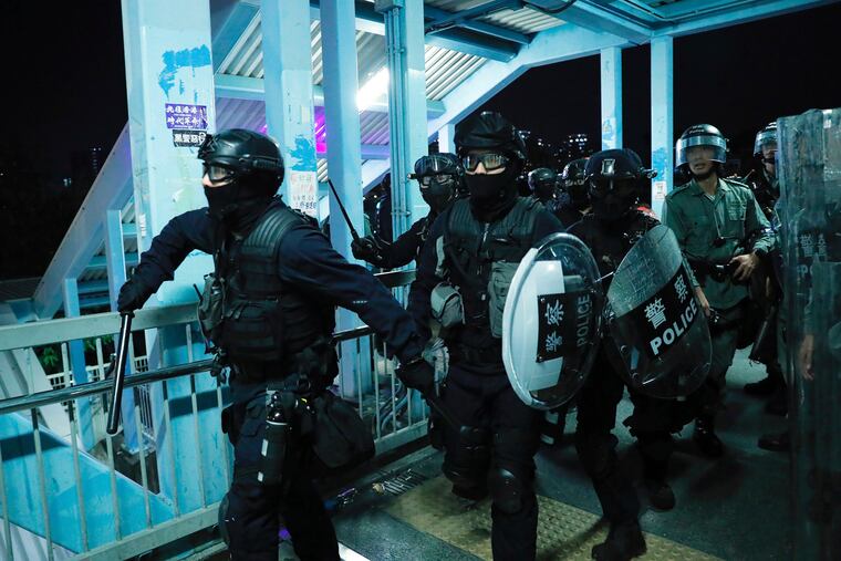 Riot police gather outside the Yuen Long MTR station during a protest in Hong Kong, Wednesday, Aug. 21, 2019. Hong Kong riot police faced off with protesters occupying a suburban train station Wednesday evening following a commemoration of a violent attack there by masked assailants on supporters of the anti-government movement.