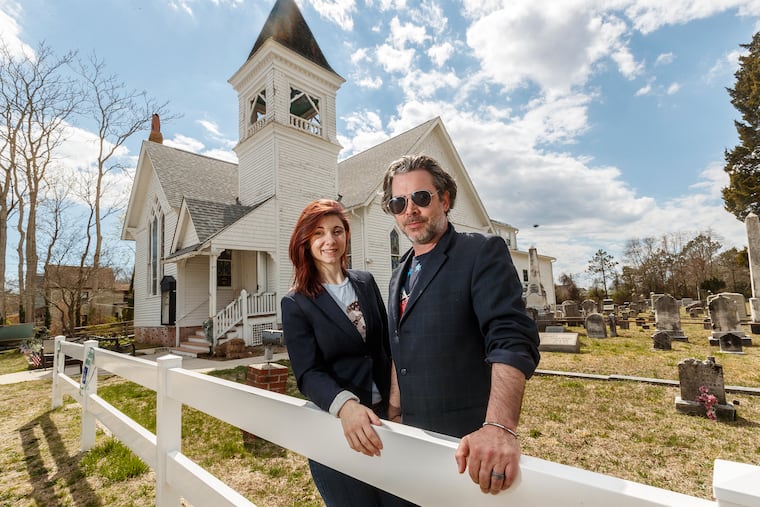 Will Keenan, right, the executive director and founder of St. Bab's, with Maura Allsman, left, the program director, in front of the cemetery and church that he bought two years ago and named after his late mother. The historic building has become a thriving spiritual, cultural, service, and advocacy center. Two Philadelphia organizations are partnering to help preserve the property on Delsea Drive in the hamlet of Goshen, Cape May County, NJ