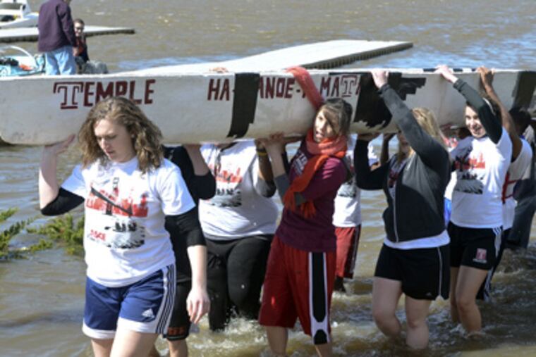 Temple University students carry their concrete canoe from the river after passing a dunk test to insure the canoe won't sink. (Ron Tarver / Staff Photographer)