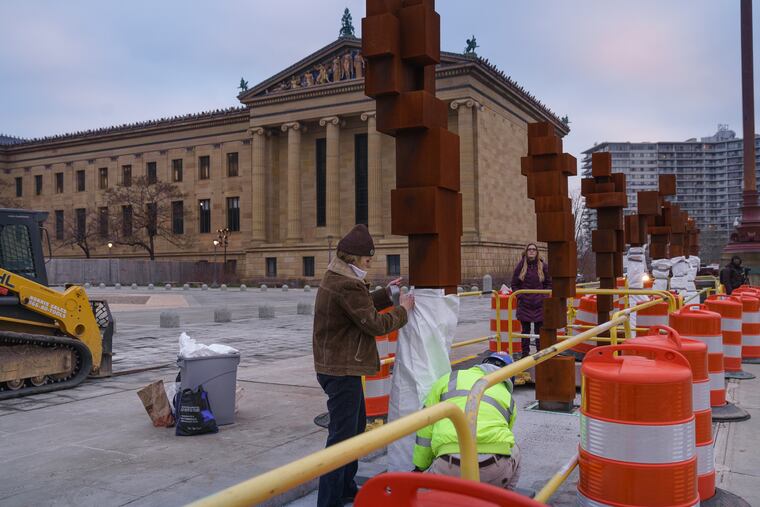 Sally Malenka, PMA conservator of sculpture and decorative arts, assists during installation of the Antony Gormley sculptures on the east terrace of the art museum Tuesday. JESSICA GRIFFIN / Staff Photographer