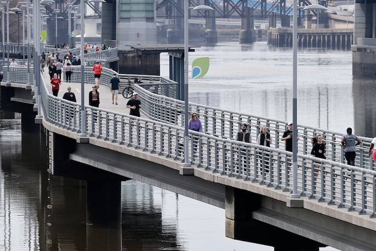 Joggers and walkers move along the Schuylkill Banks Boardwalk on Sunday. The run of record warmth is about to end.