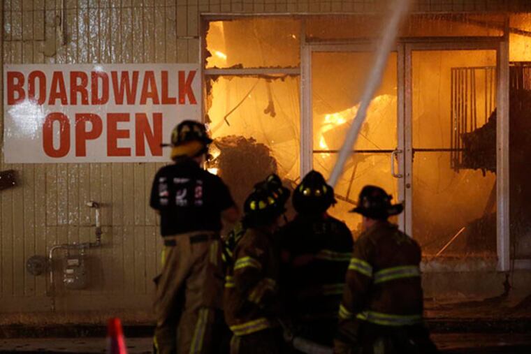 Firefighters battle a blaze in a building on the Seaside Park boardwalk on Thursday, Sept. 12, 2013, in Seaside Park, N.J. The fire began in a frozen custard stand on the Seaside Park section of the boardwalk and quickly spread north into neighboring Seaside Heights. (AP Photo/Julio Cortez)
