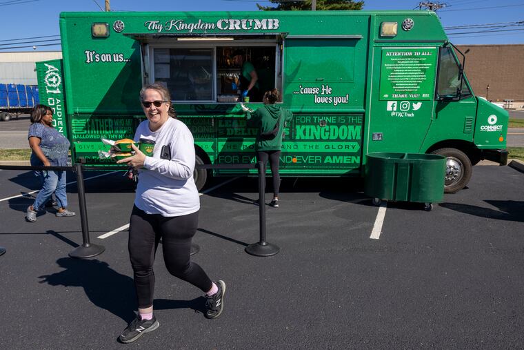 Colleen Mivelax of Cherry Hill takes two Carnitas sandwiches to her sons after picking them up from Thy Kingdom Crumb food truck parked outside the South Jersey Food Bank in Pennsauken.