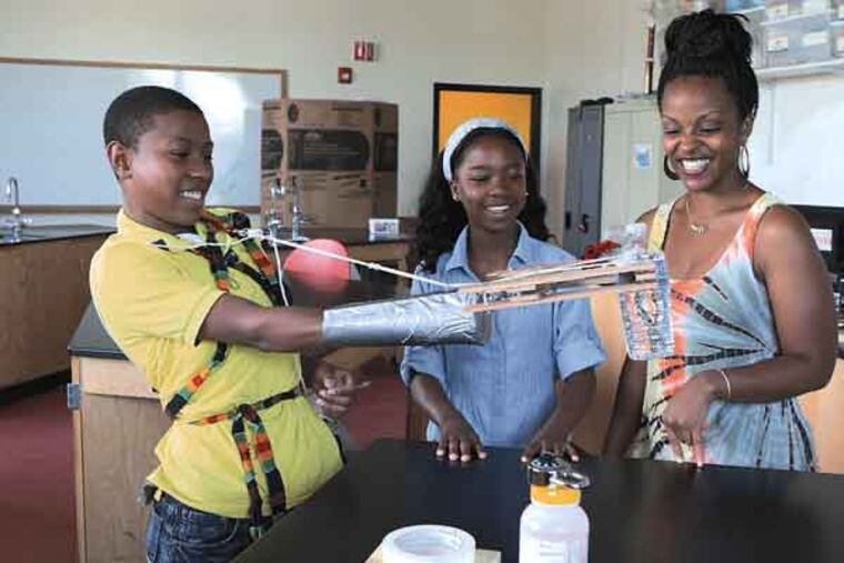 From left, Ahmed Curtis, 14, picks up a water bottle with the group's mechanical arm as Teleah Robinson, 13, and teacher Ayanna Thompas watch. A group of four 7th graders from Marambee Institute of Science and Technology won a second place in the Mathematics, Engineering and Science Achievement national competition. June 28, 2013. MICHAEL S. WIRTZ / Staff Photographer