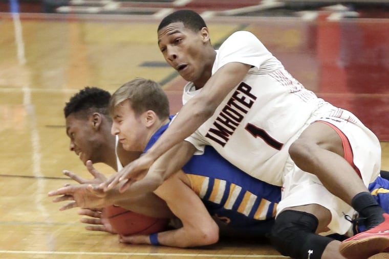 Imhotep’s Dahmir Bishop (1) lands on top of two players Friday night. Bishop ended with 13 points.
