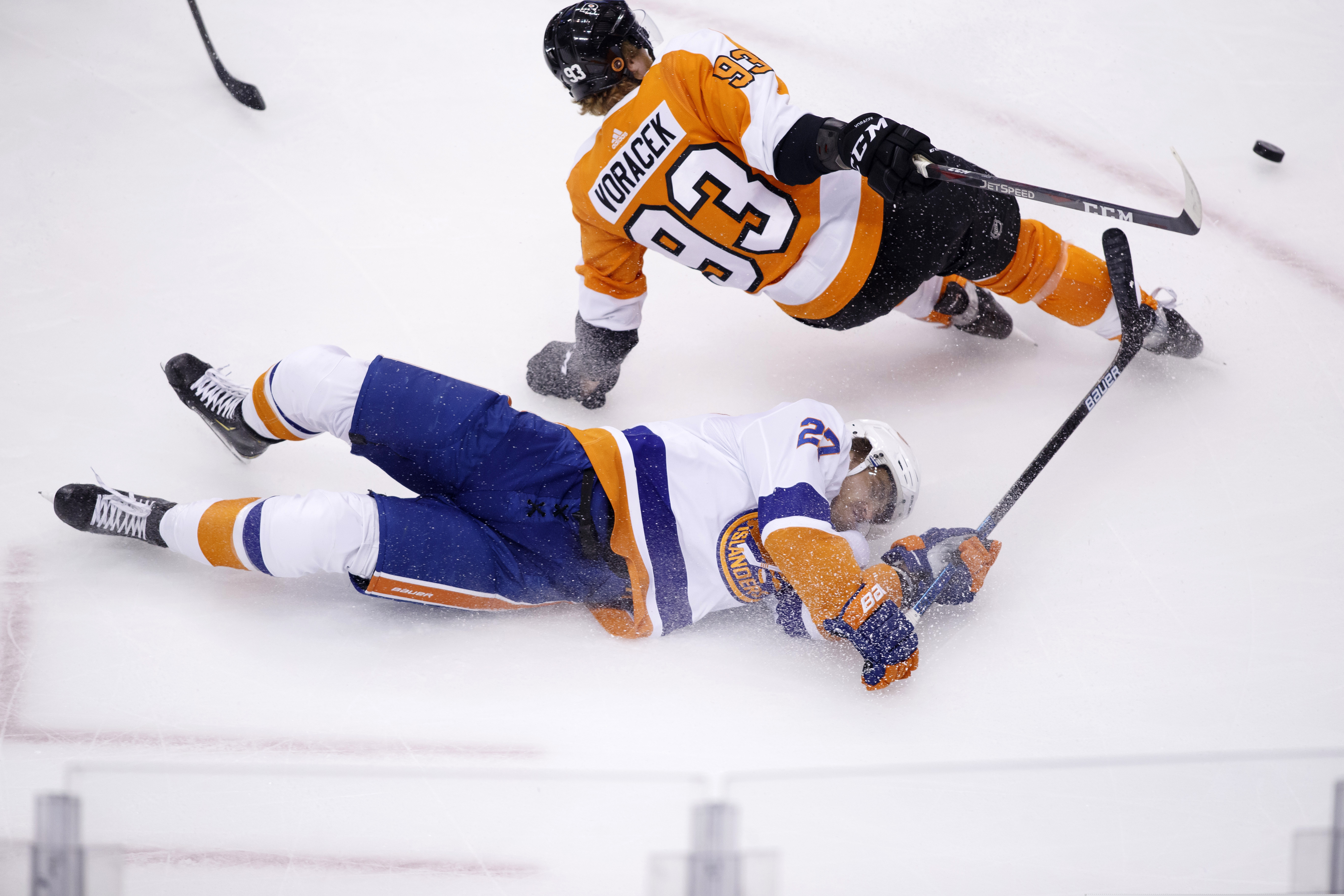 Islanders left wing Anders Lee (bottom) passes the puck as he falls to the ice near Flyers right wing Jake Voracek.