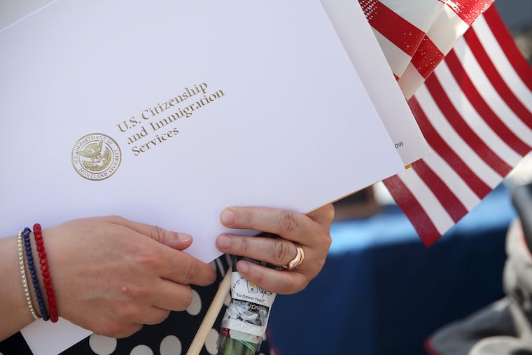 A woman from Voorhees, originally from France, holds her naturalization certificate and American flags after a naturalization ceremony on the Battleship New Jersey in Camden in 2019.