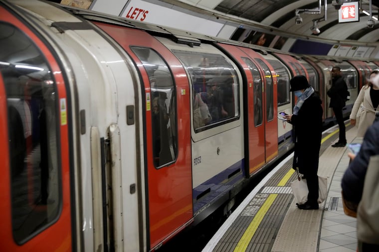 A woman wearing a face mask waits to board an underground train on the Central Line at Bank station in London, Wednesday, March 4, 2020.