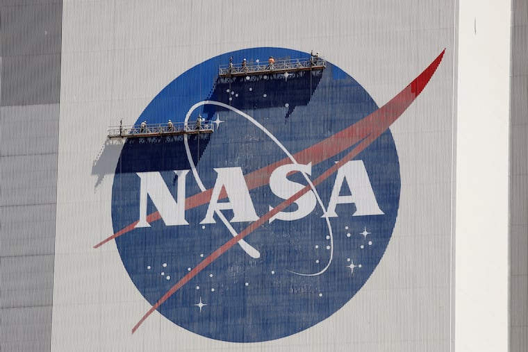 Workers near the top of the 526 ft. Vehicle Assembly Building at the Kennedy Space Center spruce up the NASA logo standing on scaffolds in Cape Canaveral, Fla., Wednesday, May 20, 2020.