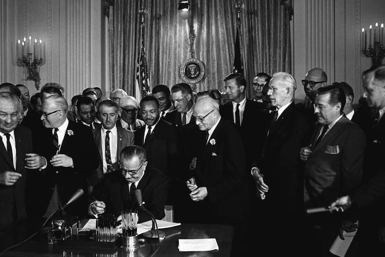President Lyndon B. Johnson signing the 1964 Civil Rights Act as Martin Luther King Jr. and others look on.