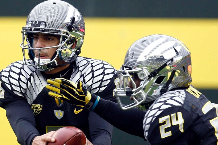 Oregon QB Marcus Mariota, handing off to Kenjon Barner, is important to the offense with his ability to run and pass. AP
