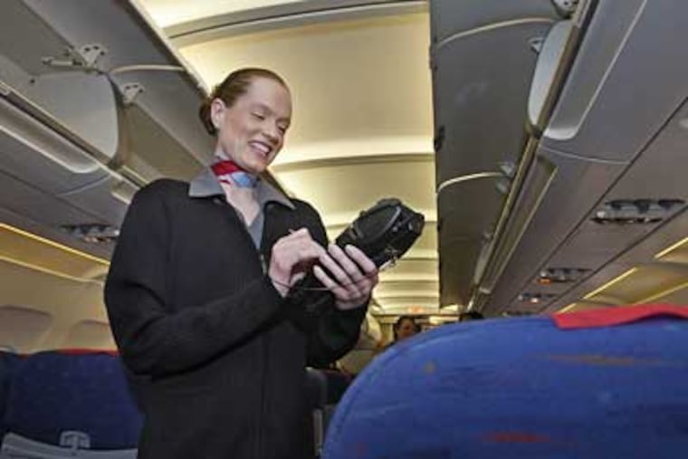 Aboard a USA3000 flight to Fort Myers, Fla., Laura Korpel, lead flight attendant, uses a handheld card reader to swipe credit or debit cards for such purchases as cocktails and headphones. (Michael S. Wirtz / Staff Photographer)