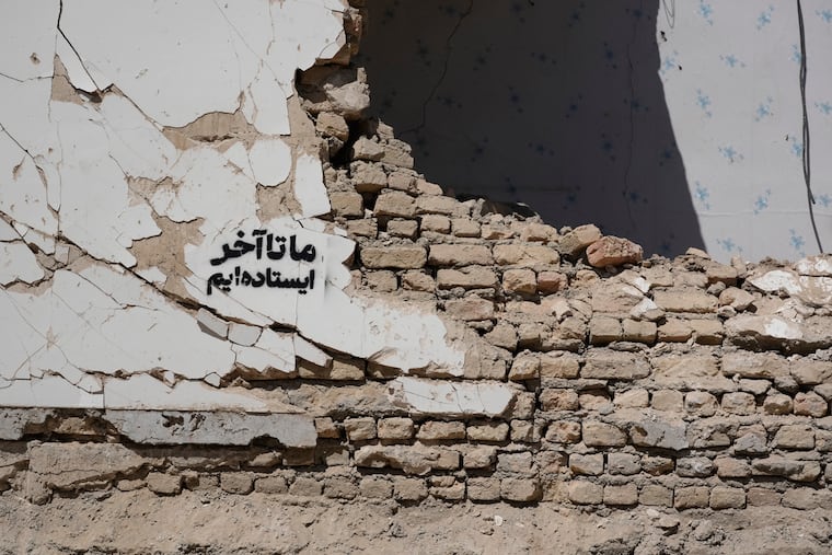 A residential building damaged by recent U.S.-Israeli strikes is seen with a sign on its wall that reads in Farsi: “We stand till the end,” in Fardis, west of Tehran, Iran, Friday, April 3, 2026.