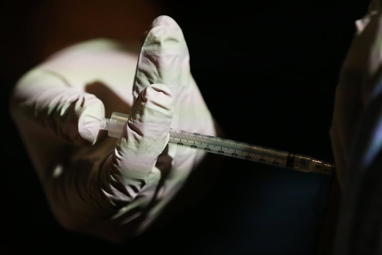 A doctor receives his first dose of the Pfizer-BioNTech COVID-19 vaccine from a nurse at Temple University Hospital on Wednesday.