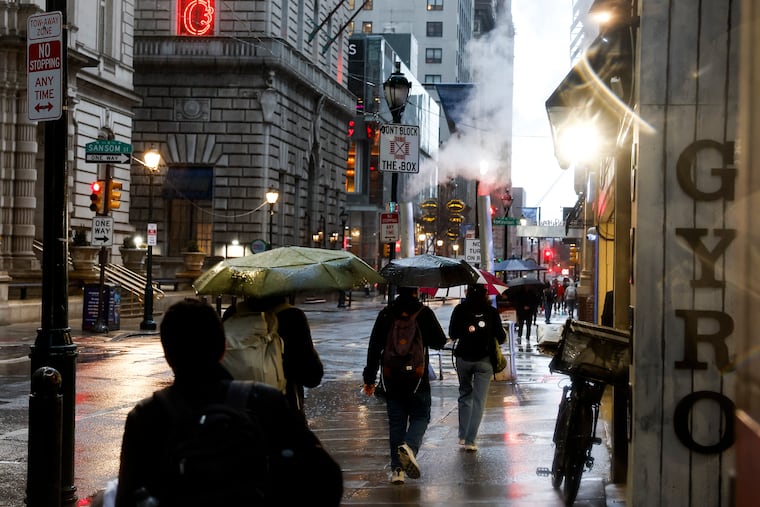 Pedestrians navigate Center City in the rain on Monday. Those rains may have spared the region some mayhem.