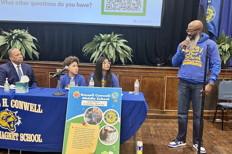 Philadelphia School District Deputy Superintendent Oz Hill and student moderators Devyn Smith and Yoleiny Soleno listen to Andre Sanford-Adams, the school's health and physical education teacher, speak about why he thinks it's a mistake to close Conwell.
