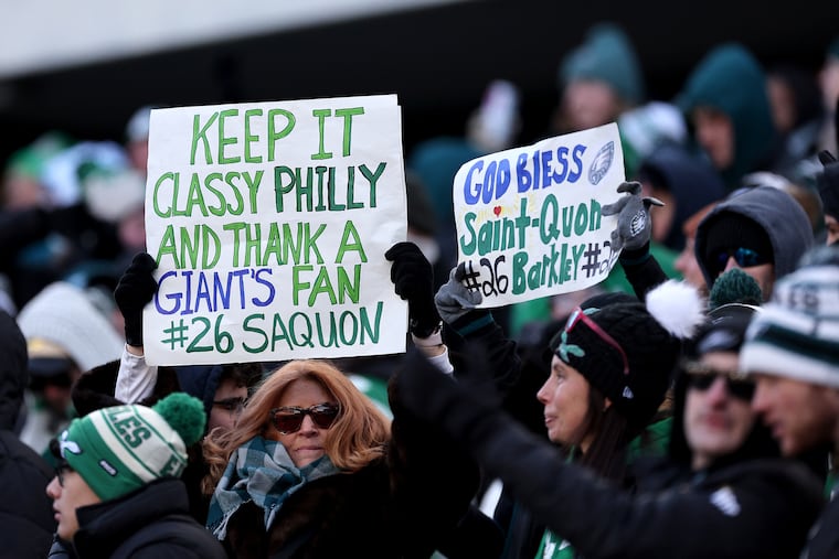Spectators hold up signs as the Eagles play the New York Giants at Lincoln Financial Field in Philadelphia on Sunday, Jan. 5, 2025.