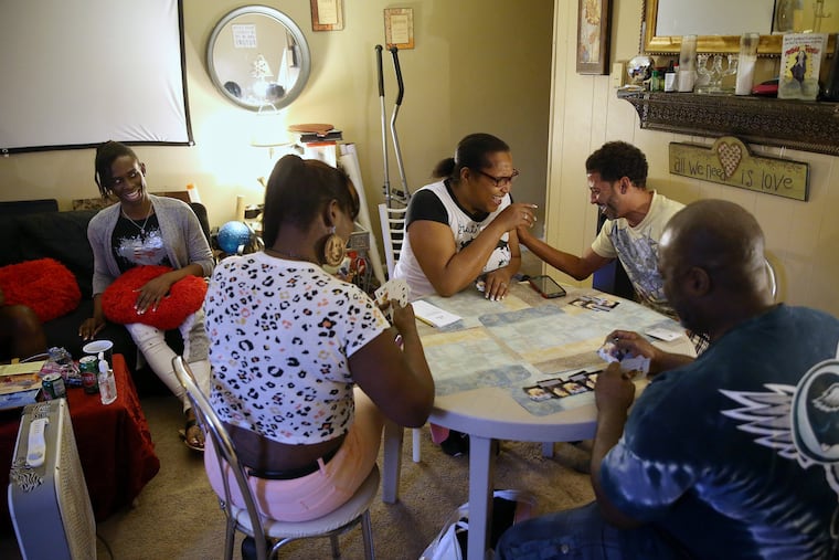 From left, Tiffany Lollis watches as Saniya Lamour, Andrea Lamour-Harrington, James Cosky, and Doug Vanlue Jr. play a game of spades during a gathering at Lamour-Harrington and Vanlue's home in Brookhaven on Saturday.