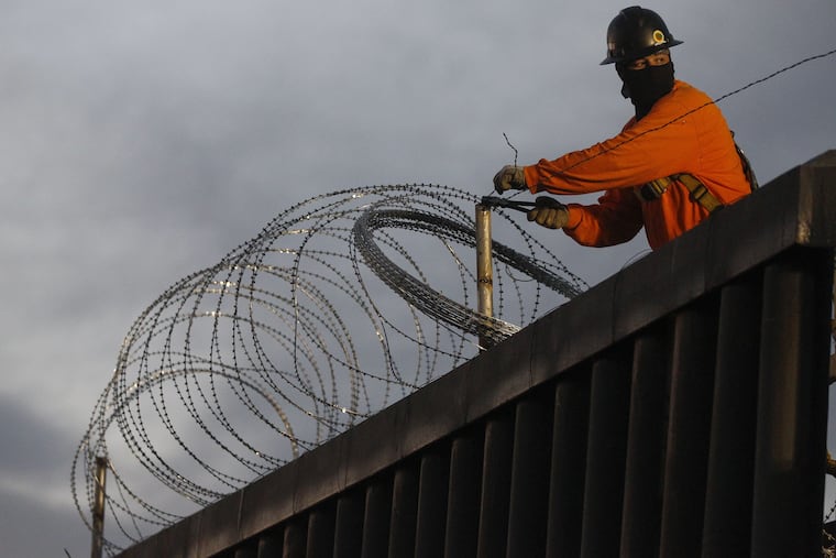 A worker on the U.S. side of the Mexican border installs razor wire at Playas de Tijuana earlier this month.