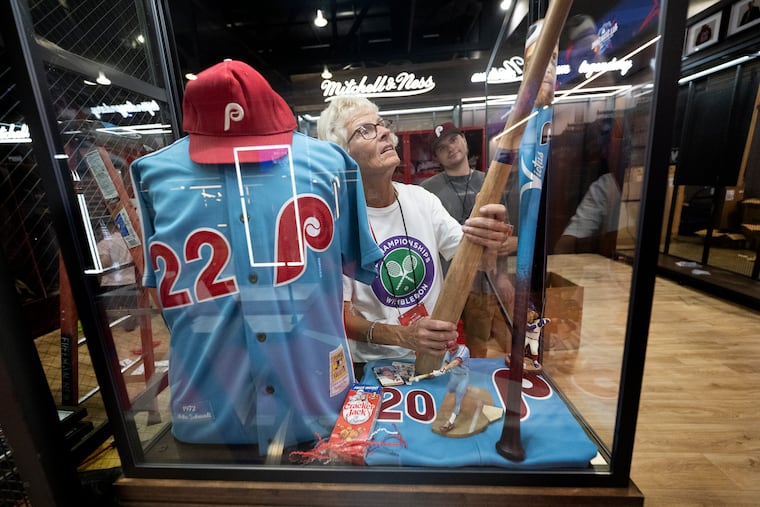 Joanne Graham decorates an exhibit featuring vintage Phillies gear for the Fanatics booth at the MLB All-Star Village inside the Pennsylvania Convention Center in Philadelphia.
