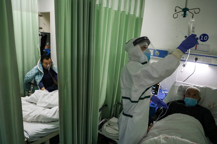 In this Thursday, Feb. 6, 2020, photo, a nurse checks on a patient in the isolation ward for 2019-nCoV patients at a hospital in Wuhan in central China's Hubei province. The number of confirmed cases of the new virus has risen again in China on Saturday, Feb. 8, 2020, as the ruling Communist Party faced anger and recriminations from the public over the death of a doctor who was threatened by police after trying to sound the alarm about the disease over a month ago.