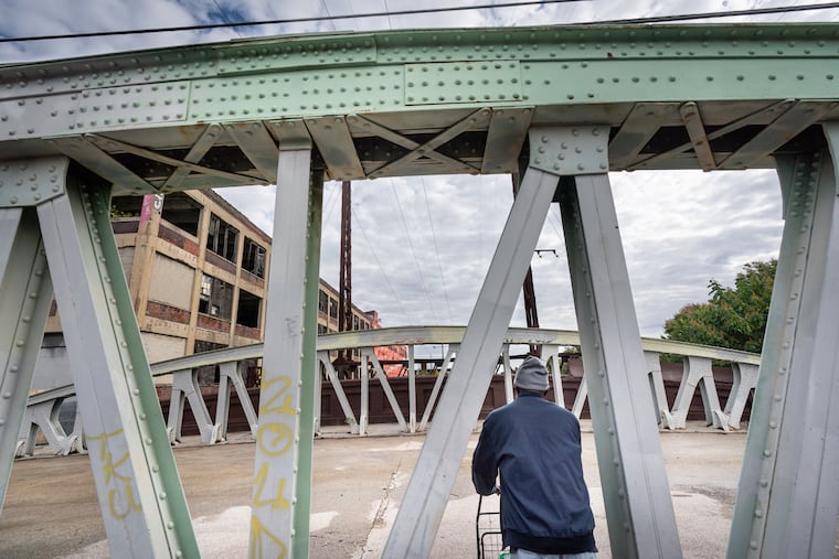 A pedestrian walks on the Margie Street bridge over Amtrak's Northeast Corridor in North Philadelphia on Friday. New money from the federal infrastructure law will enable the city ultimately to repair 18 bridges across electrified rail tracks.