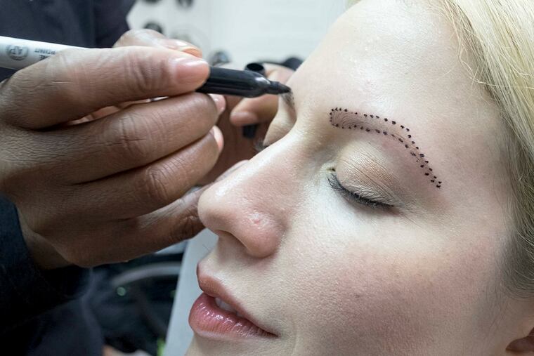 Ursula Augustine marks the outline of Miriam Ort's eyebrows with a series of dots at the Center City boutique Ursula's About Phace.