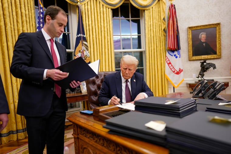 Will Scharf, White House staff secretary, stands beside the Resolute Desk as President Donald Trump signs executive orders on Jan. 20.