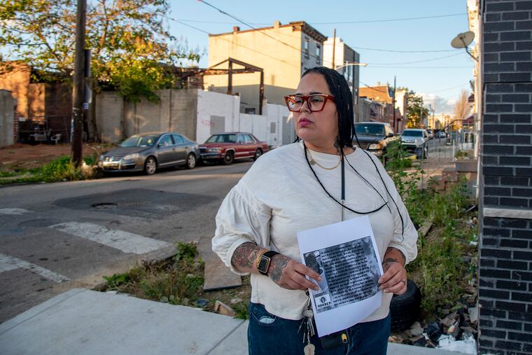 Carmen Pagan poses Nov. 10, 2020 with a flyer she has been distributing, on the corner where her 20-year-old son was recently shot three times. He survived, but she's been struggling to keep him away from the streets for years. She's now hitting the streets trying to find out who shot him, but her son continues to slip away.