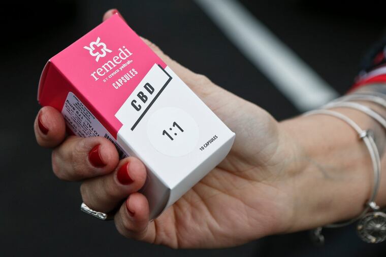 FILE -A woman holds the prescribed medical marijuana product used to treat her daughters epilepsy after making a purchase at a medical marijuana dispensary in Butler, Pa. Two new studies released on Monday, April 2, 2018 suggest that legalization of marijuana may reduce the prescribing of opioids.