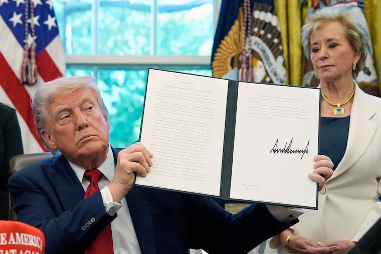 President Donald Trump holds a signed executive order relating to school discipline policies as Education Secretary Linda McMahon listens, in the Oval Office on April 23.