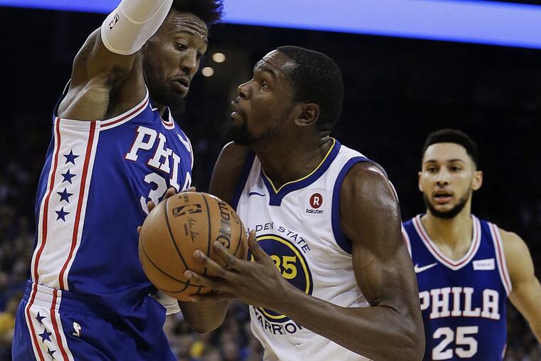 Golden State’s Kevin Durant, center, drives against 76ers Robert Covington, left, as Ben Simmons watches.
