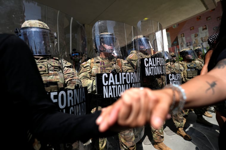 Protesters clasp hands in front of a line of California National Guard on Monday at a federal building in downtown Los Angeles.