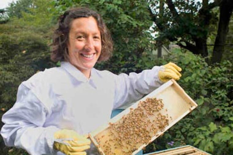 Nicole Juday, Wyck horticulturist, with a frame from her home hive. Gelato made from Wyck's honey will be served there on Saturday. (Ed Hille / Staff Photographer)