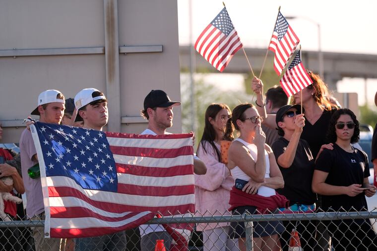 People watch a hearse containing the body of Charlie Kirk, who was shot and killed on Wednesday, at Phoenix Sky Harbor International Airport on Thursday, Sept. 11.