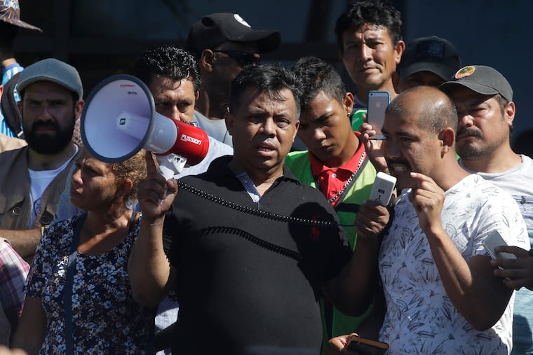 FILE - In this Oct. 22, 2018 file photo, migrant activist Irineo Mujica, center, of the group Pueblo Sin Fronteras or People Without Borders, holds a megaphone as a Central American migrant speak to reporters during a press conference in Tapachula, Mexico. The activist group that escorted thousands of Central Americans to the U.S. border is under fire from allies and some of the migrants themselves. They say the organization downplayed the dangers of the trek and misled them about how long they would have to wait around to apply for asylum. Pueblo Sin Fronteras, or People Without Borders, is defending itself, saying the migrants made their own decision to press on toward the United States. (AP Photo/Moises Castillo)