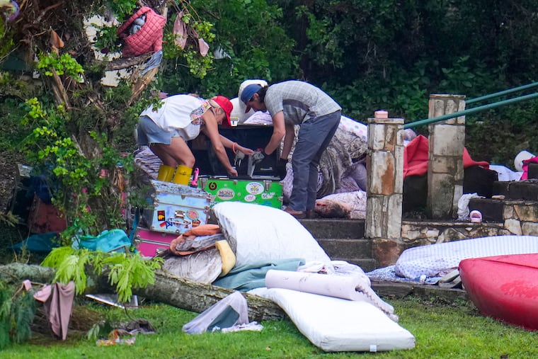 People look through belongings on a camp trunk at Camp Mystic along the banks of the Guadalupe River after a flash flood swept through the area on Sunday, July 6, 2025.