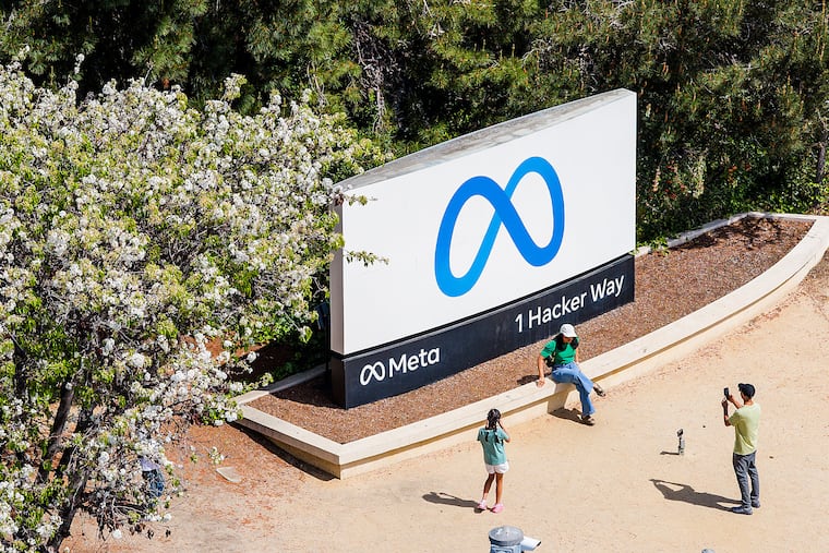 FILE - Visitors take photos at a sign outside Meta headquarters March 26, 2026, in Menlo Park, Calif. Meta receently notified about 8,000 employees that they would be laid off.